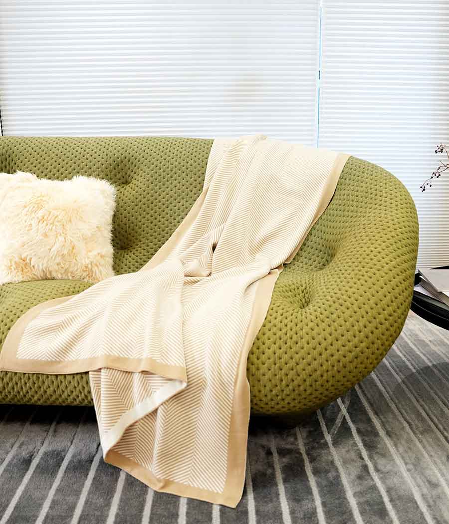 Throw blanket in brown beige with stripe patterns on a sofa