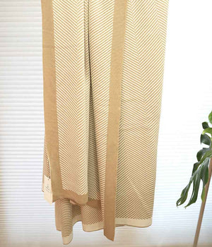 Throw blanket in brown beige with stripe patterns hung on rack