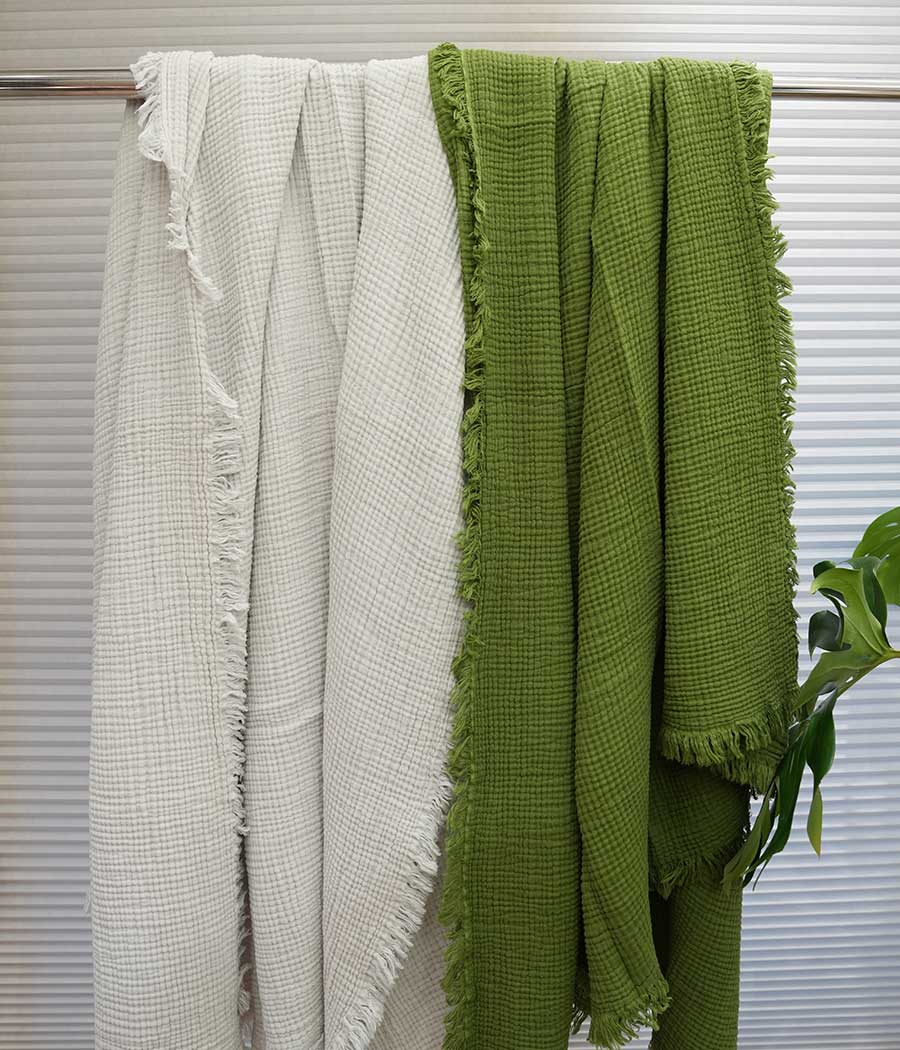 silver grey and green cotton blankets hung on rack next to each other