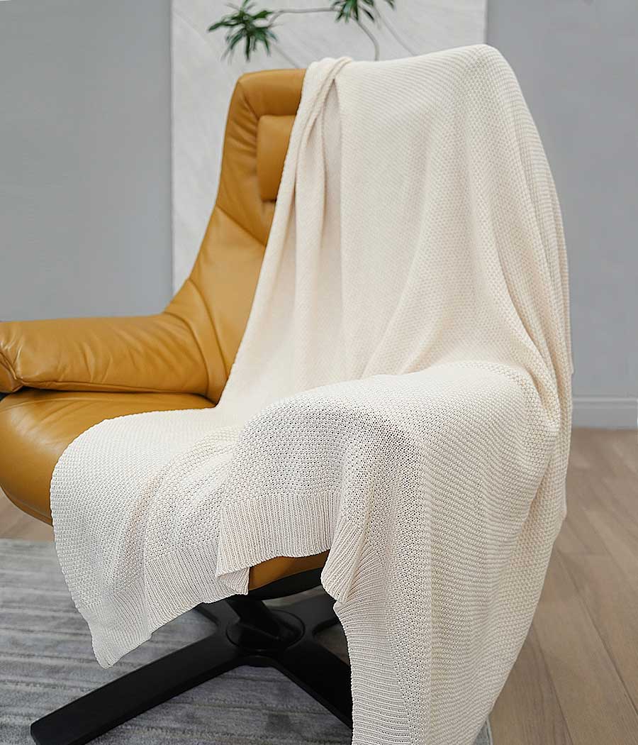 Knit throw blanket in beige on a chair