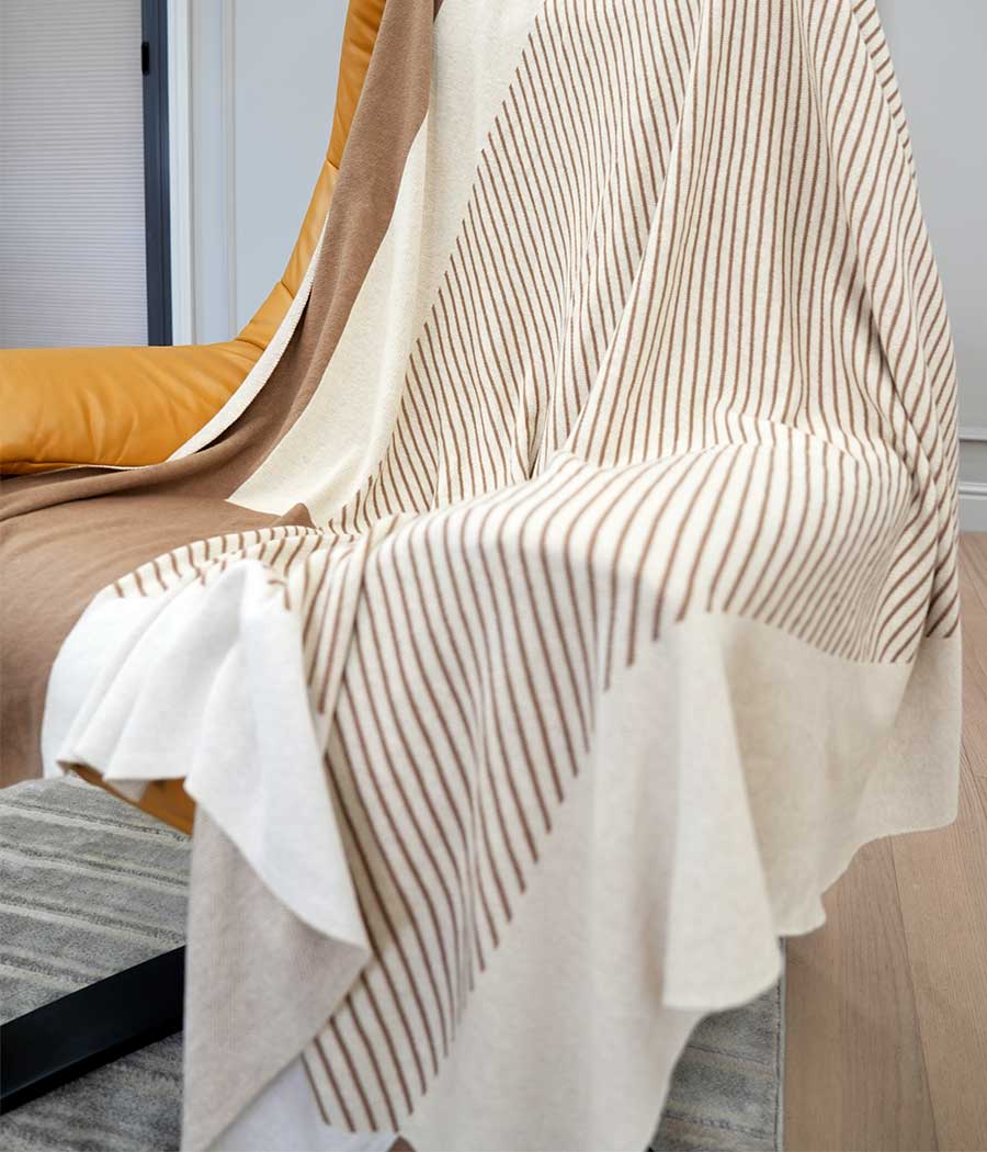 Wool blend throw blanket in camel and beige with stripe patterns putting on chair